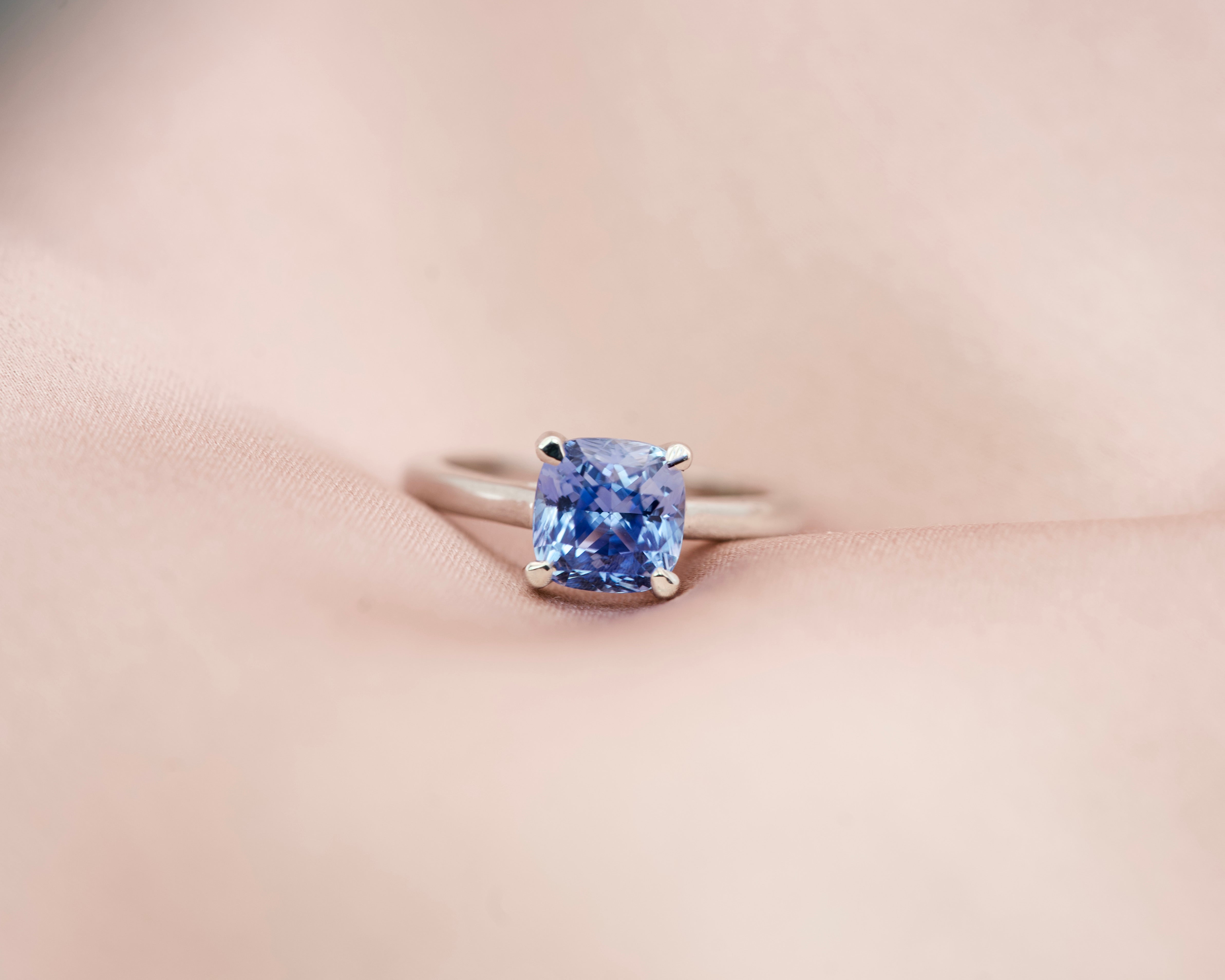 2.02 ct unheated Ceylon sapphire cushion cut ring resting on soft pink silk