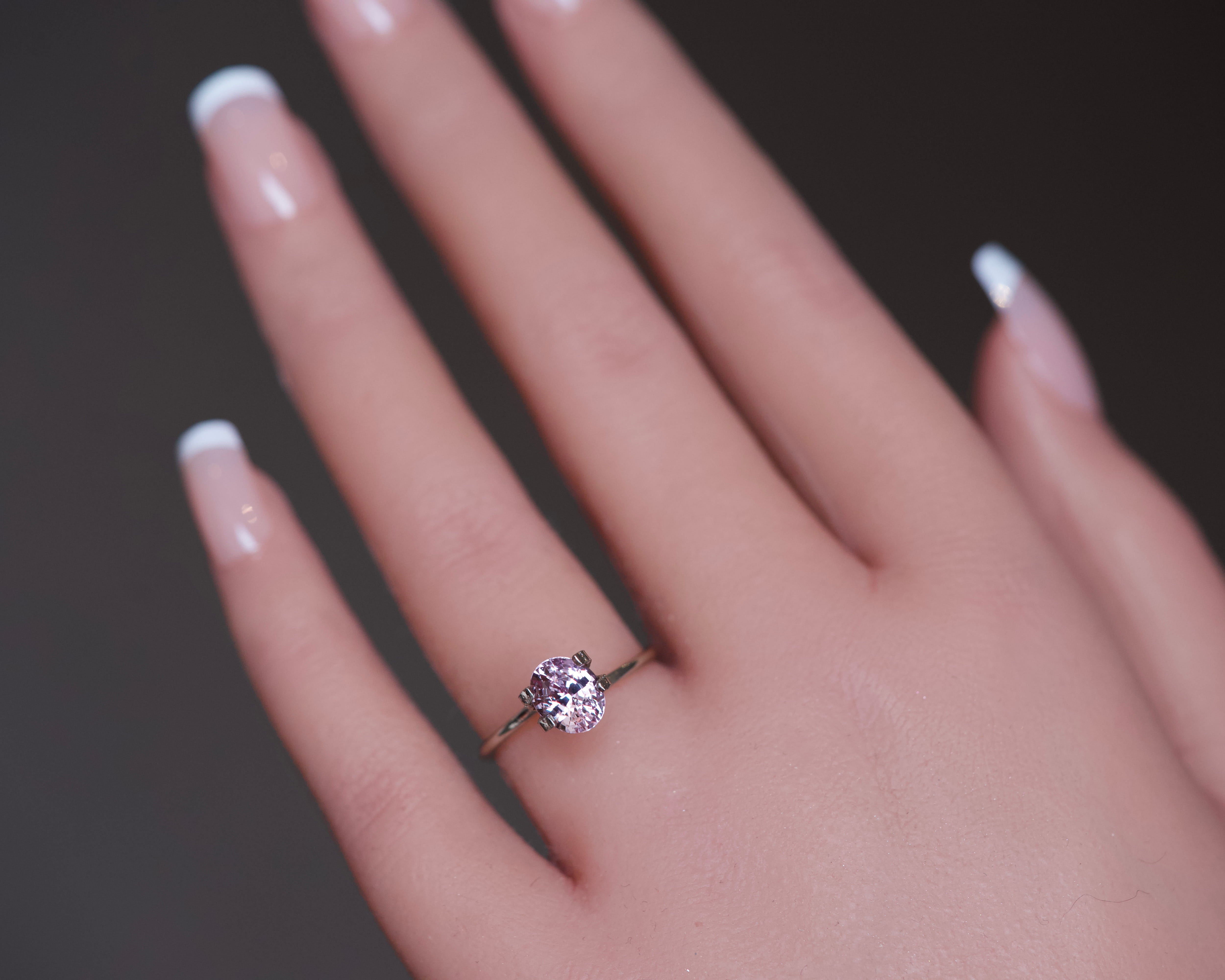 Oval mixed-cut violetish orangish pink pastel sapphire shown as a ring mockup on a finger.