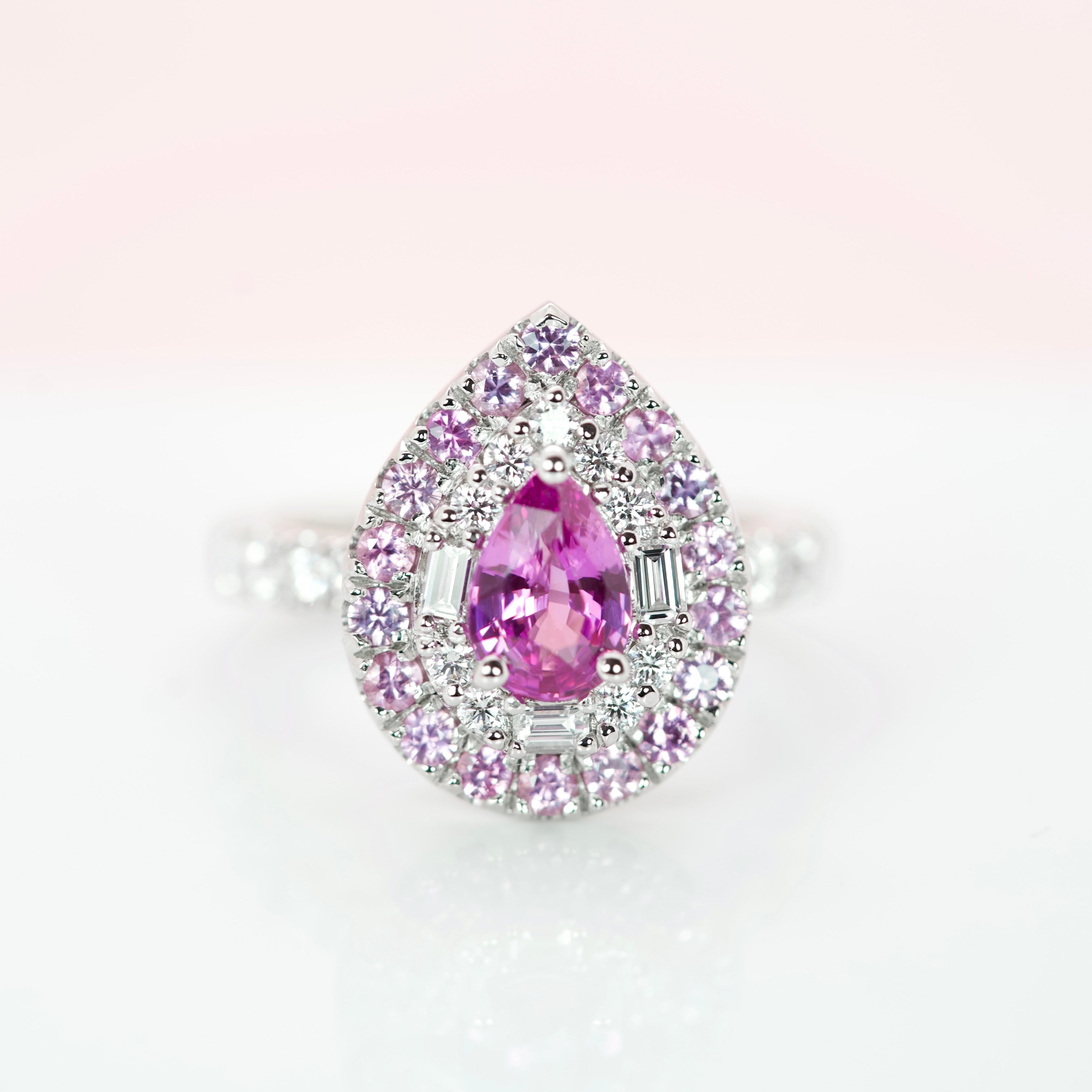 Frontal macro view of a 1.27 ct pear pink sapphire with baguette diamond halo and pink sapphire border