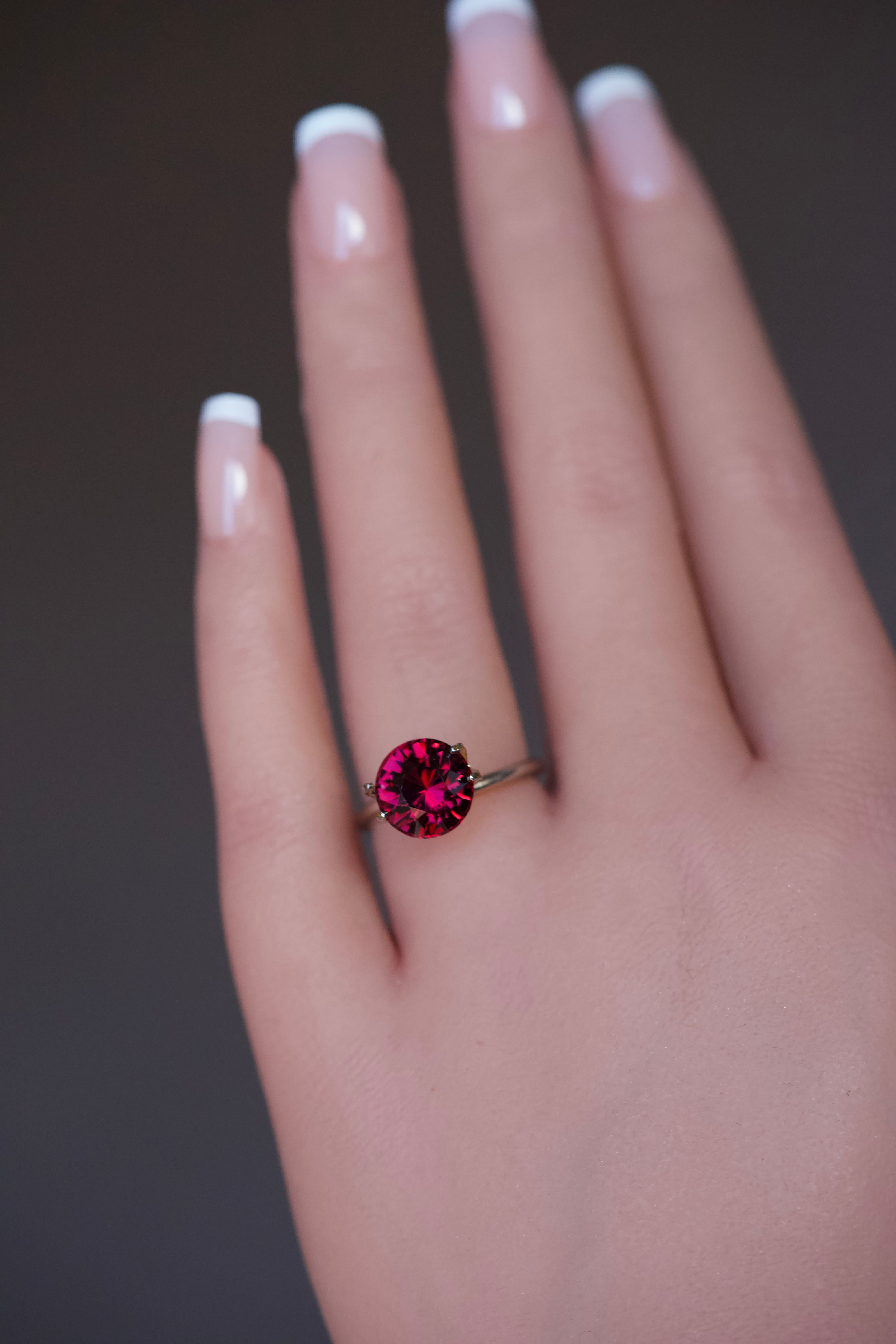 Round purplish pink rhodolite stone modeled in a simple prong setting.
