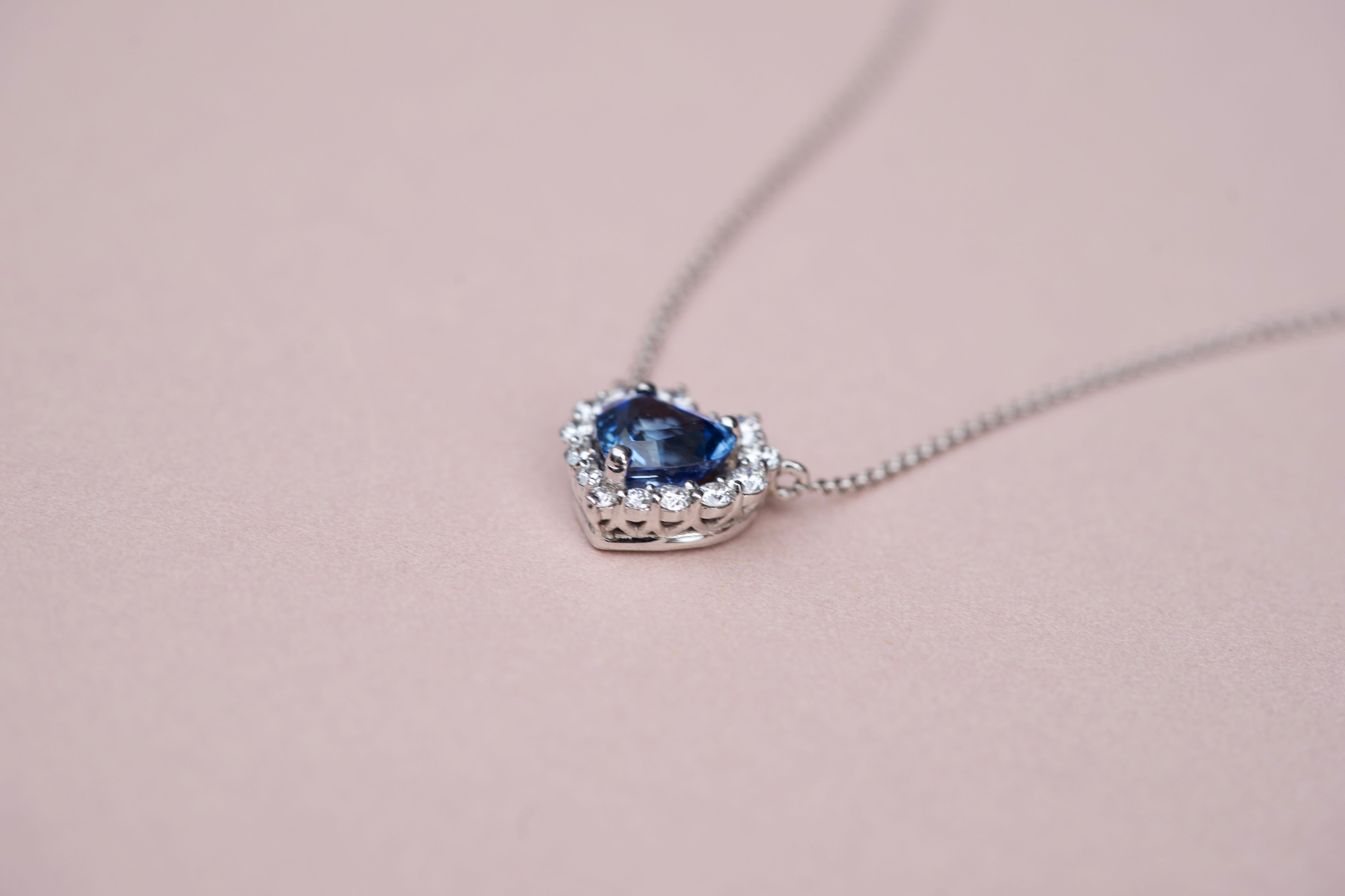 Side profile detail of the 18k white gold basket setting on a blue sapphire heart pendant